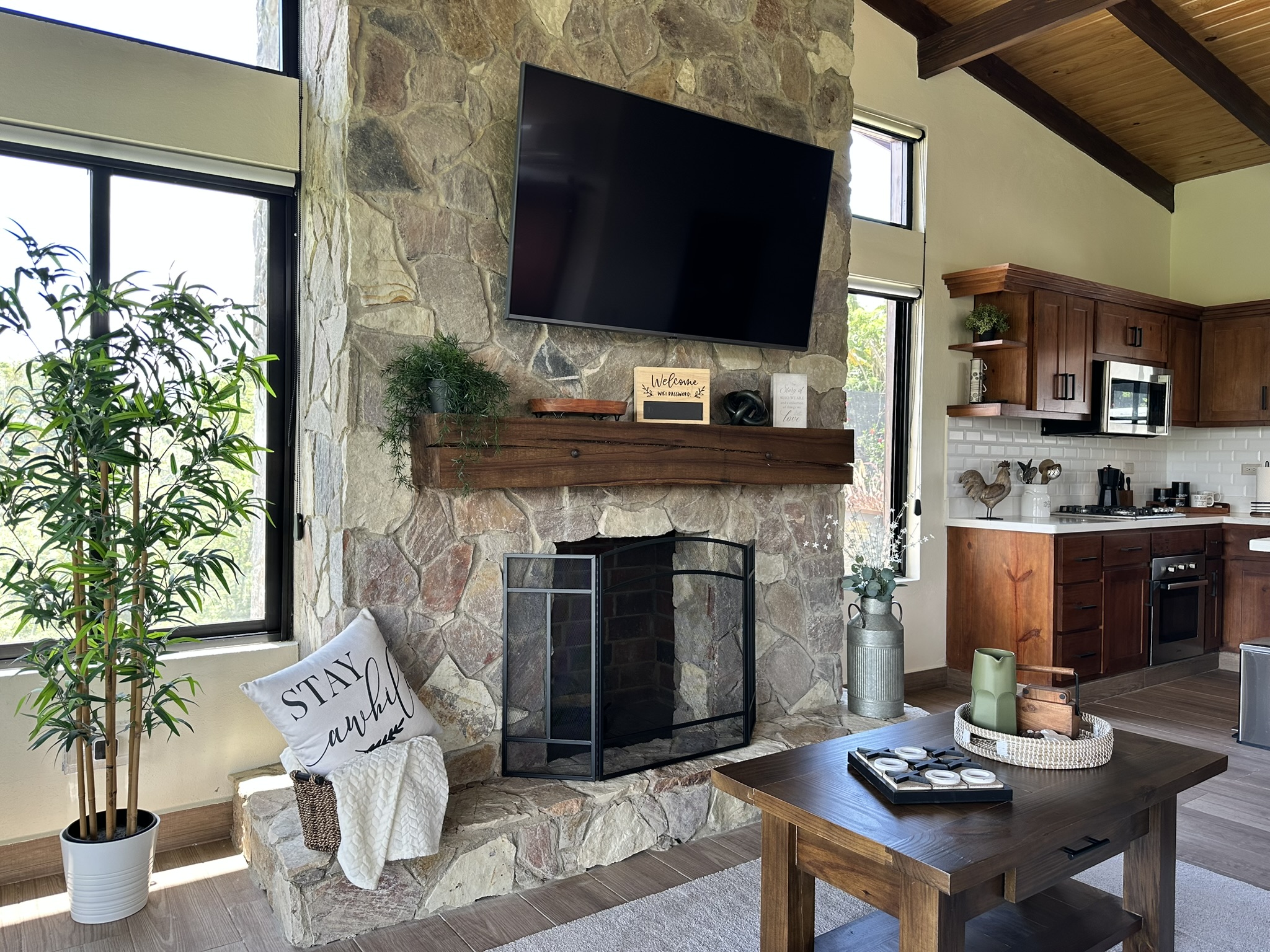 Sala de la cabaña con chimenea de piedra y cocina abierta